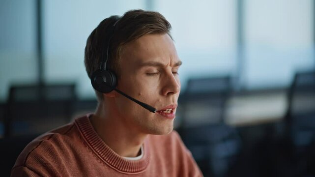 Serious helpdesk assistant talking headset in office coworking space closeup
