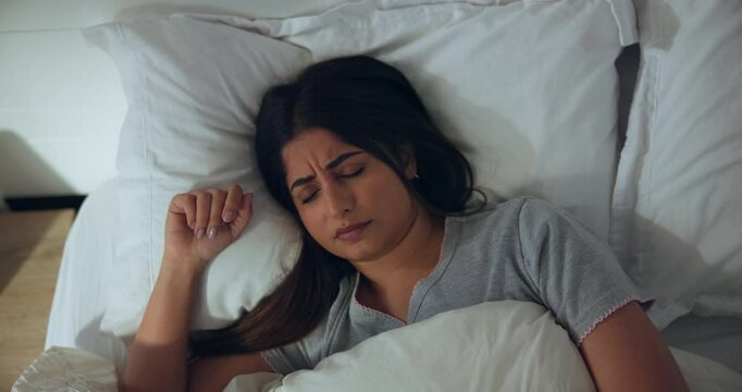 Above, woman and restless sleep in bed with nightmare, tired or fatigue with fright at home. Scared, fear and female person in bedroom asleep with bad dream, wake up or frown with sleepless problem