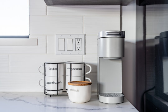 Pod single serve coffee maker with white cups and sugar in kitchen