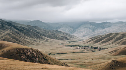 Mountain valley with cloudy sky and small village in distance