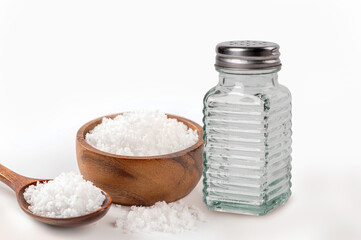 Salt shaker with salt in wooden bowl isolated on white background.