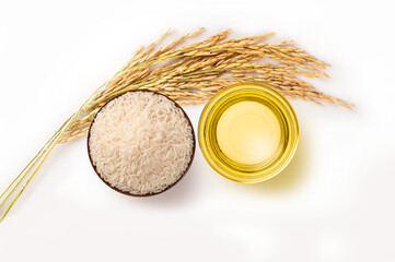 Rice bran oil in glass bowl with rice ears on white background.