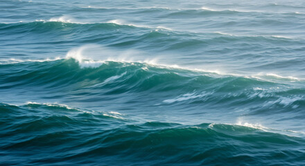 Fototapeta premium Powerful, deep blue ocean waves with whitecaps cresting in the wind. A dynamic and natural background showing the raw energy of the sea. 