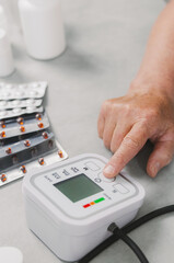 An elderly woman turns on a blood pressure monitor.