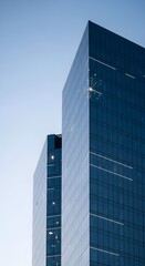 Naklejka premium Modern blue glass facade, towering skyscraper, contemporary urban architecture, clear sky