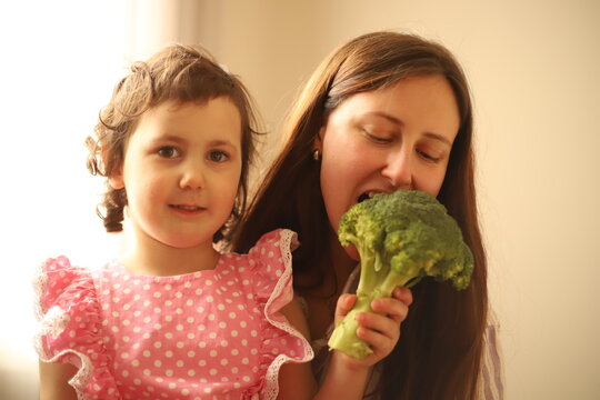 mother and daughter holding broccoli