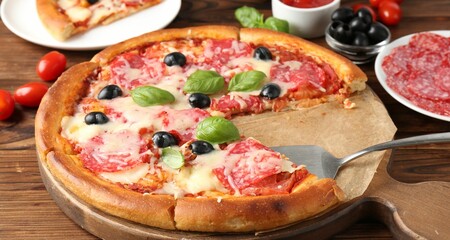Tasty pizza and ingredients on wooden table, closeup