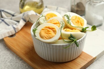 Hard boiled eggs with microgreens on grey table, closeup