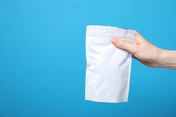 Woman with zipper stand-up pouch on light blue background, closeup. Mockup for design