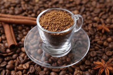 Cup with granulated instant coffee, star anise and cinnamon on beans, closeup