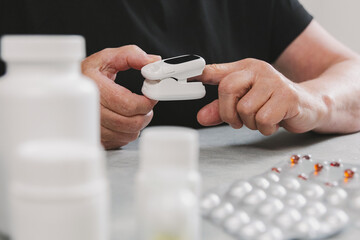 An elderly woman measures her pulse with a device.