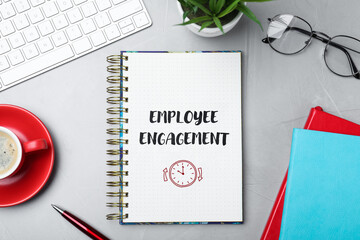 Employee engagement. Words and drawing in notebook on office desk, top view
