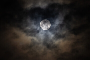 Full moon in the dark night sky with clouds 