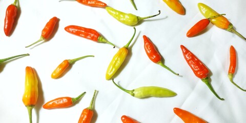 Pattern of Assorted Chili Peppers, From Mild Yellow to Fiery Red, Laying Flat Against a White Surface, Suitable for Backgrounds, Banners, or Spicy Food Promotions