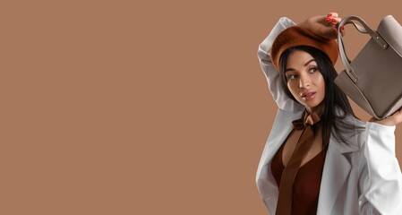 Stylish young woman holding bag on brown background with space for text