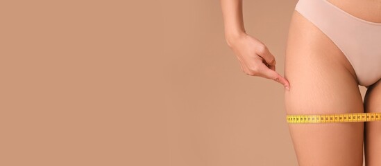 Beautiful young woman with stretch marks on her body and measuring tape against beige background...