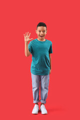 Little African-American boy waving hand on red background