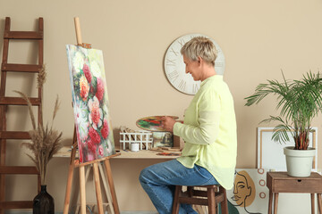 Mature female artist painting picture in  workshop