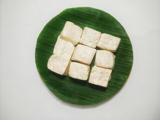 Minimalist Composition of Raw Tofu Cubes on a Vivid Green Banana Leaf, Emphasizing Simplicity and Natural Ingredients, Perfect for Clean Eating and Organic Themes