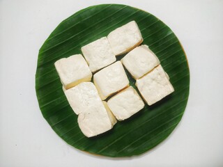 Overhead View of Freshly Cut White Tofu Cubes, Neatly Arranged on a Vibrant Green Banana Leaf, Isolated on a Clean White Background, Ideal for Vegan or Vegetarian Cuisine Concepts