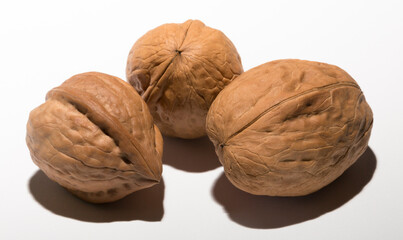 Three walnuts on a white background. The shell consists of three lobules.