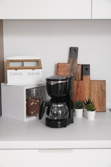 White kitchen countertop with coffee maker, cutting boards and utensils