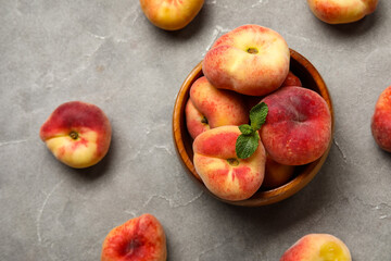 Bowl with sweet fig peaches and mint on grey background