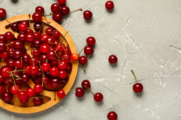 Wooden board with red sweet cherries on grey background