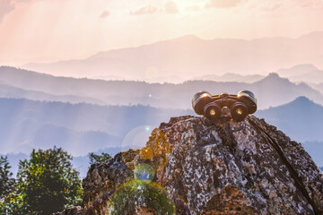 binoculars on top of rock mountain at sunset