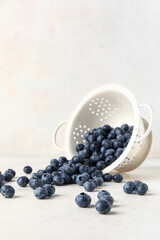 Colander with fresh blueberries on white background