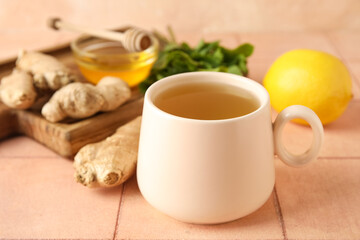 Cup of ginger tea and bowl with honey on pink tile table