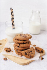 Tasty cookies with chocolate chips and glass of milk on white background