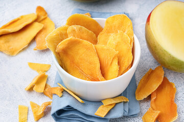 Bowl with slices of dried mango on white background