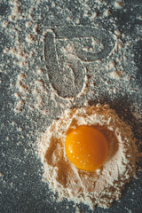 Fresh egg yolk in a nest of flour with a heart drawn in the dusted surface, symbolizing love for cooking and baking at home