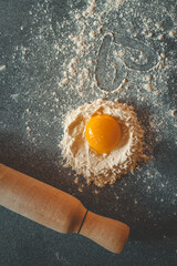 Fresh egg yolk in a nest of flour with a heart drawn in the dusted surface, symbolizing love for cooking and baking at home