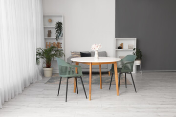 Interior of spacious living room with table, chairs, sofa, houseplants and shelving unit