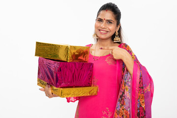 Excited and surprised Indian happy young woman holding gift boxes and standing on white. wearing...