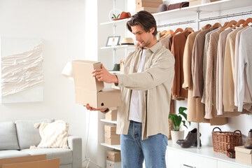 Handsome young happy man with wardrobe box and stylish clothes in dressing room