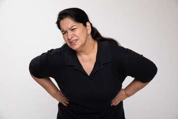 Portrait of an indian unhealthy mature woman sitting holding her stomach pain, abdominal pain,...