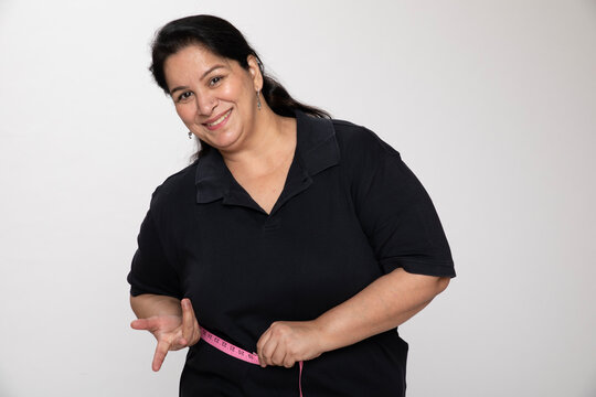 Indian happy matured woman measuring waist with a inch tape trying to lose weight isolated on white studio background