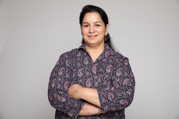 Indian middle age woman wearing white shirt standing over isolated white background happy face smiling with crossed arms looking at camera