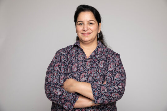 Indian middle age woman wearing white shirt standing over isolated white background happy face smiling with crossed arms looking at camera