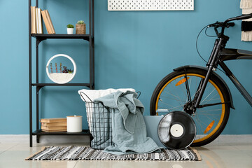 Bicycle, shelving unit and basket with cloth near blue background