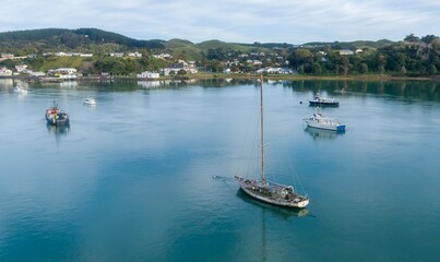 Fototapeta premium An aerial view of boats anchored in Kawhia Harbour, Kawhia, Waikato, New Zealand. The boats are various sizes, with a town visible on the shoreline. The scene is peaceful and serene.