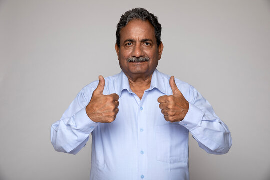 Portrait of an indian happy senior man showing thumbs up feels freedom, after retirement