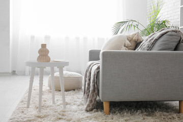 Coffee table with vase near sofa in interior of living room