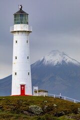 Cape Egmont Lighthouse stands tall on the coast of Pungarehu, Taranaki, New Zealand, guiding ships safely. The iconic landmark is set against the backdrop of Mount Taranaki.