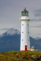Cape Egmont Lighthouse stands tall on the coast of Pungarehu, Taranaki, New Zealand, guiding ships safely. The iconic landmark is set against the backdrop of Mount Taranaki.