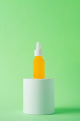 Plastic yellow tube for cream or lotion. Skin care or sunscreen cosmetic with stylish props on green background.