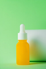 Plastic yellow tube for cream or lotion. Skin care or sunscreen cosmetic with stylish props on green background.